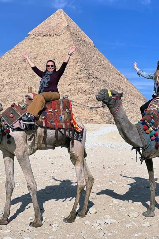 two women on camels in front of Egyptian pyramid